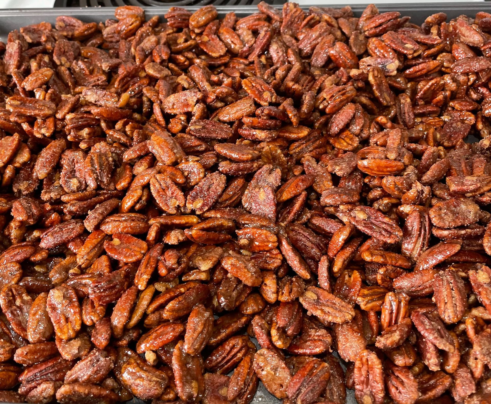 A pan filled with roasted pecans is sitting on a table.