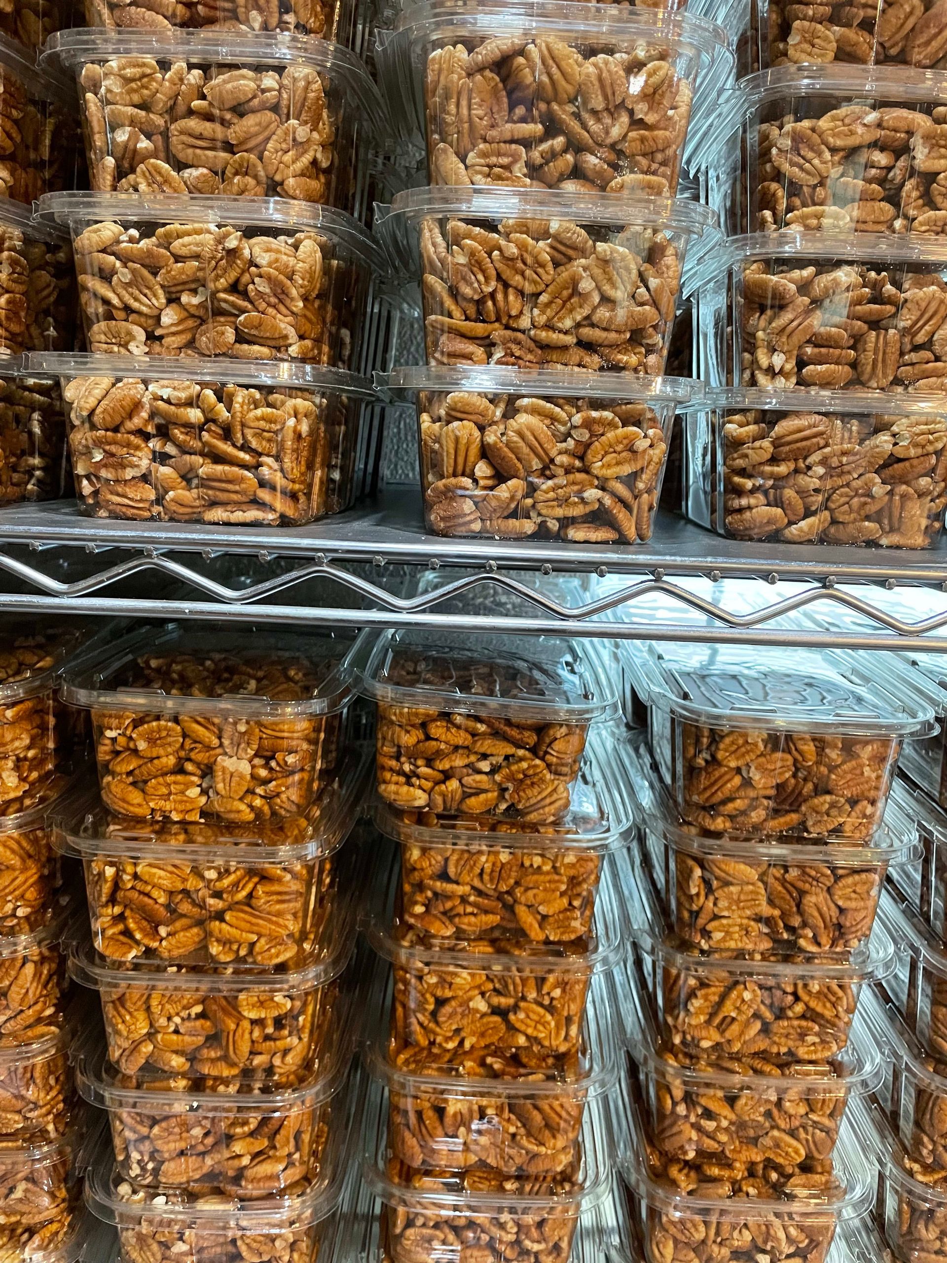 A bunch of plastic containers filled with nuts are stacked on top of each other on a shelf.