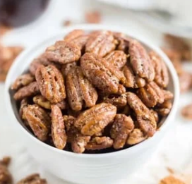 A white bowl filled with pecans on a table.