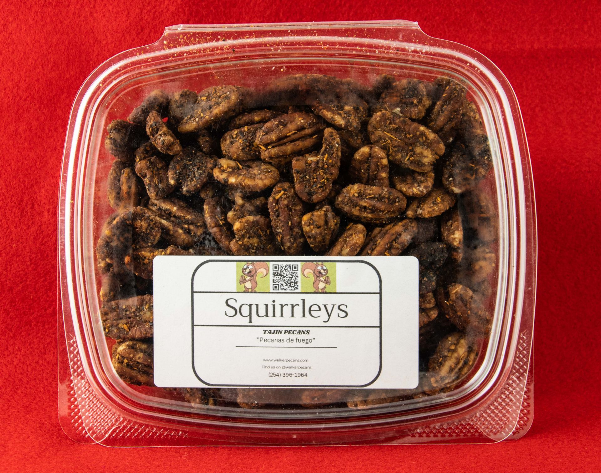 A plastic container of squirrelley 's pecans on a red background