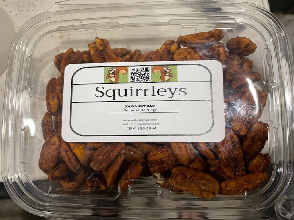 A plastic container of squirrelleys pecans on a table