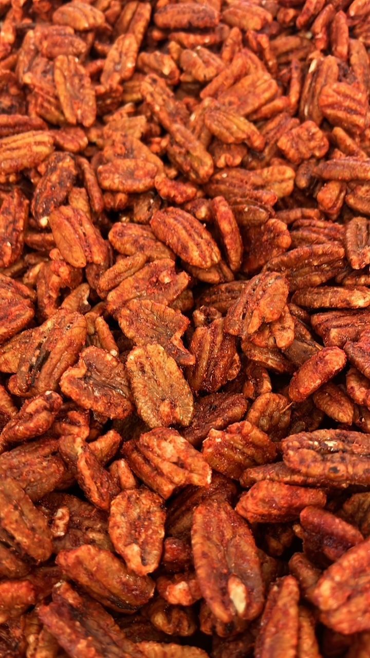 A close up of a pile of pecans covered in sauce.