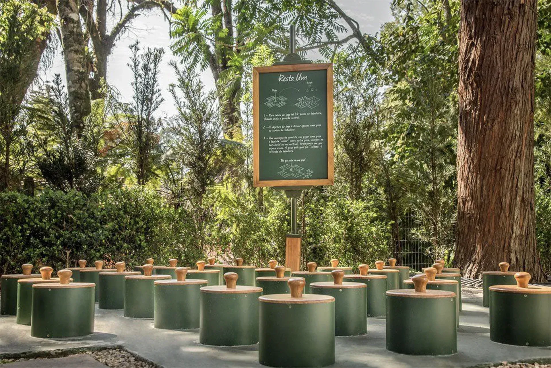 Memorial ao ar livre com castiçais verdes dispostos ao redor de uma placa de giz entre as árvores.