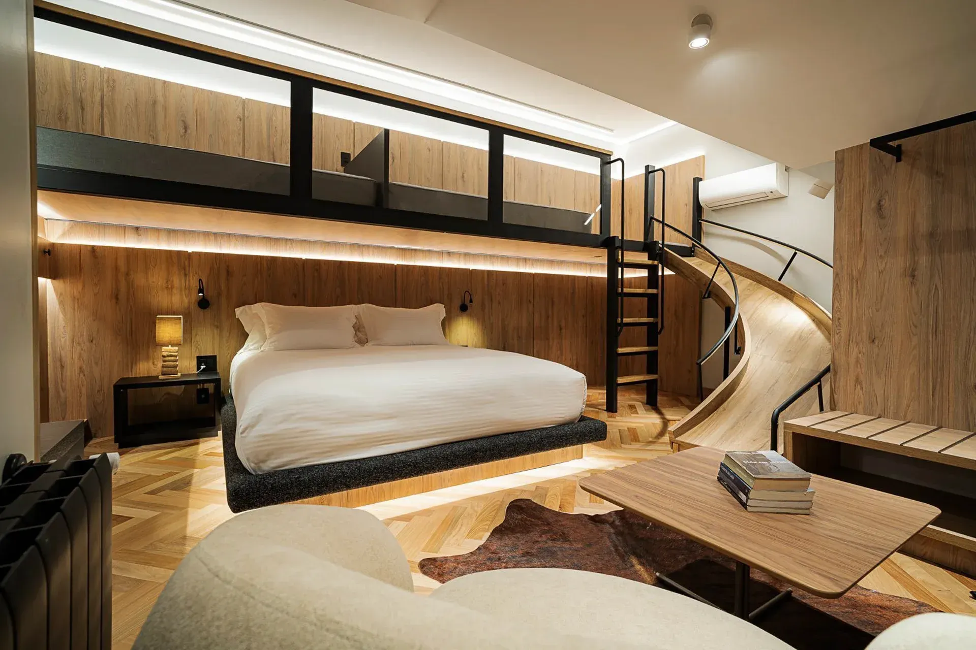 Quarto moderno em estilo loft com detalhes em madeira, cama baixa, mezanino com beliche e escada curva.