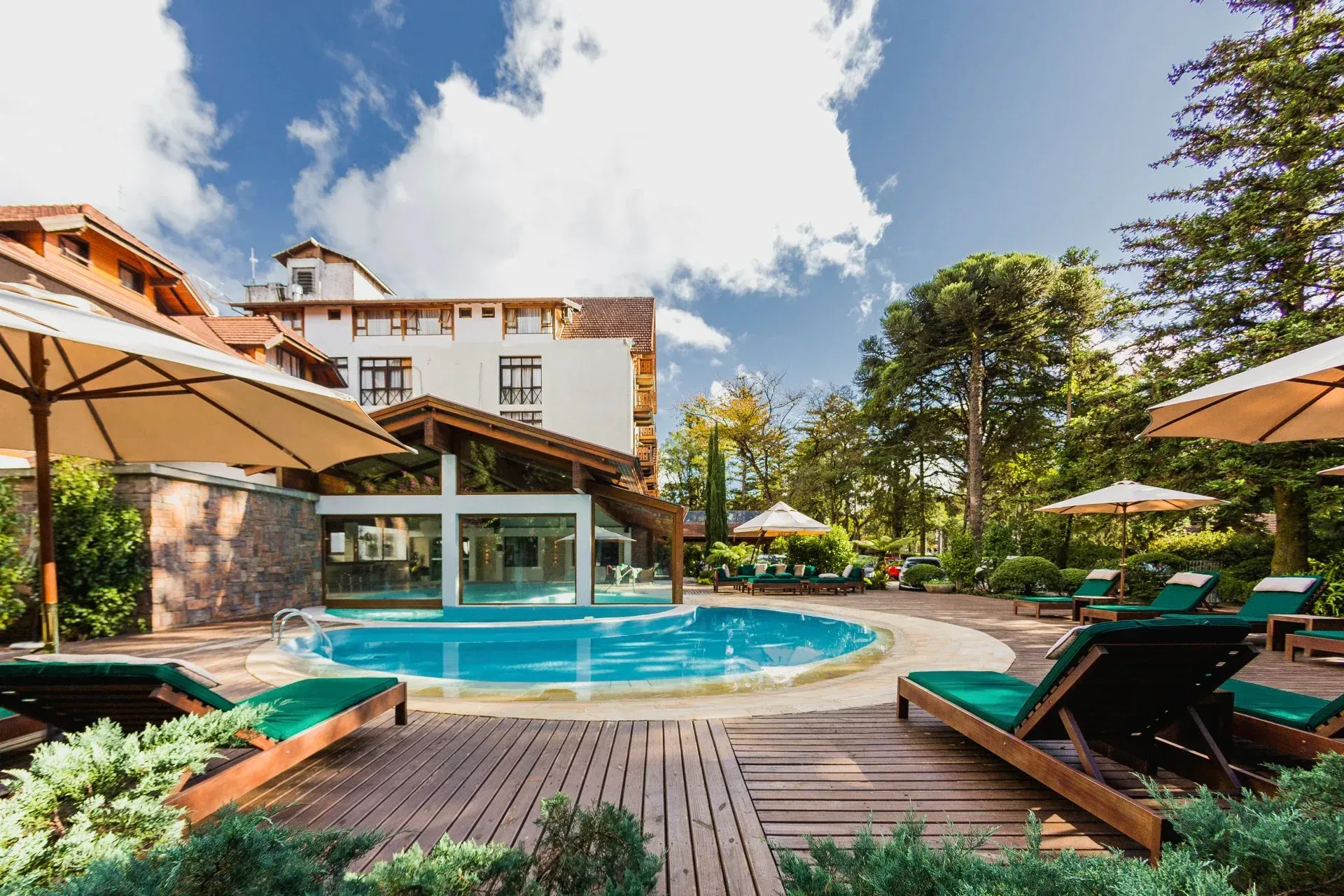 Piscina do resort com espreguiçadeiras, guarda-sóis e o prédio do hotel sob um céu azul brilhante.