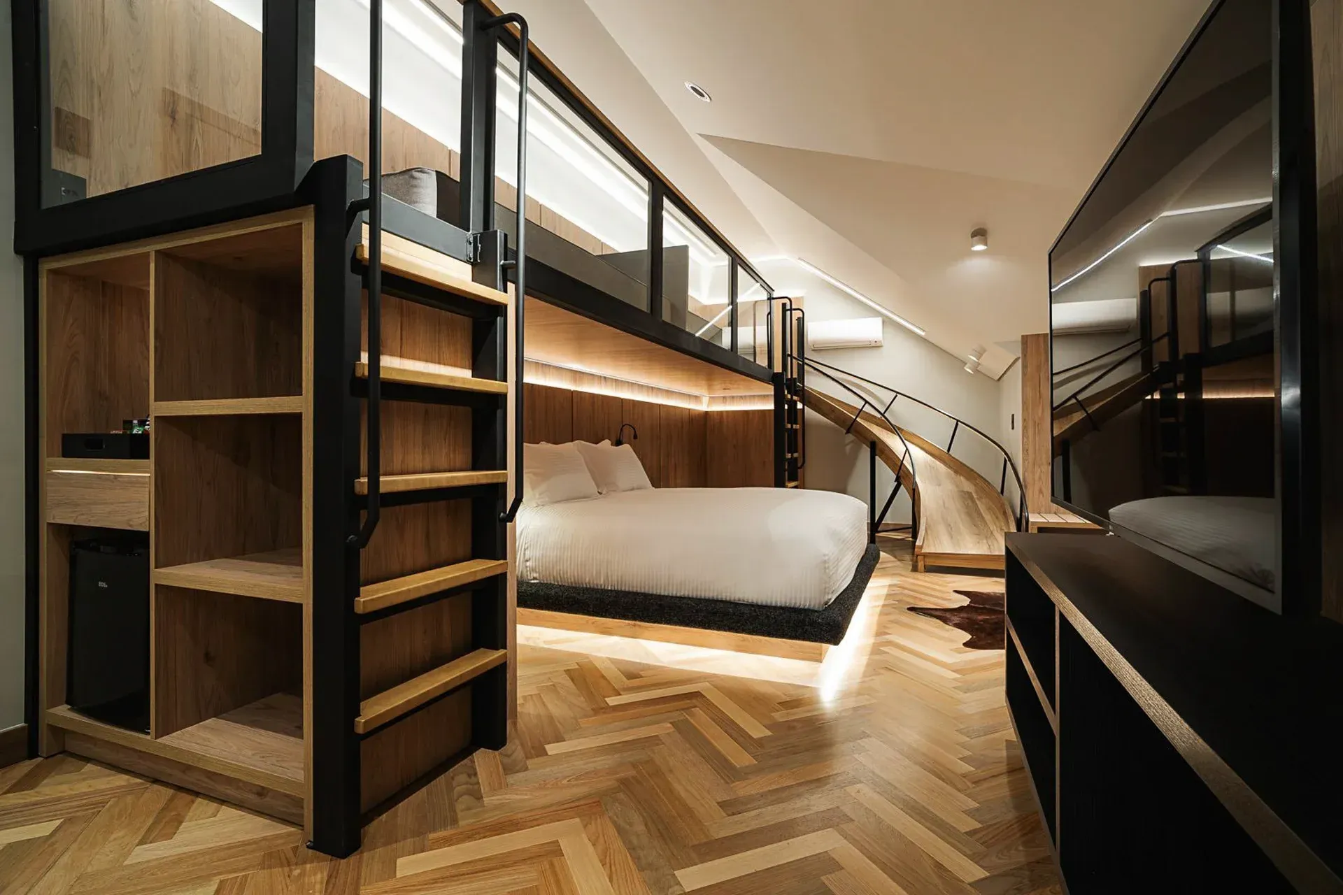 Quarto moderno em estilo loft com beliches de madeira, escada e interior aconchegante com painéis de madeira.