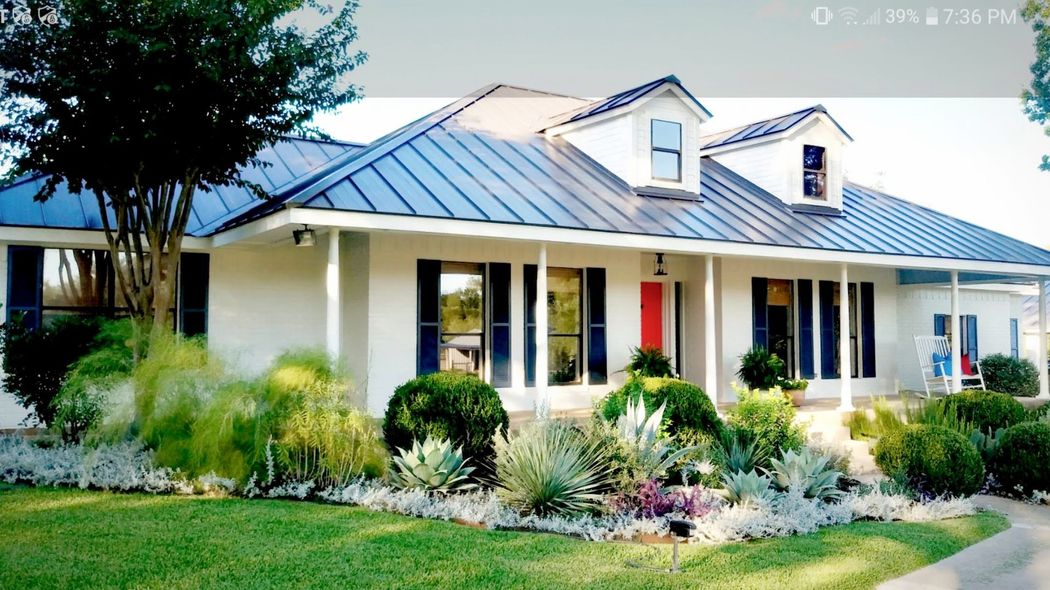 A white house with a metal roof and black shutters