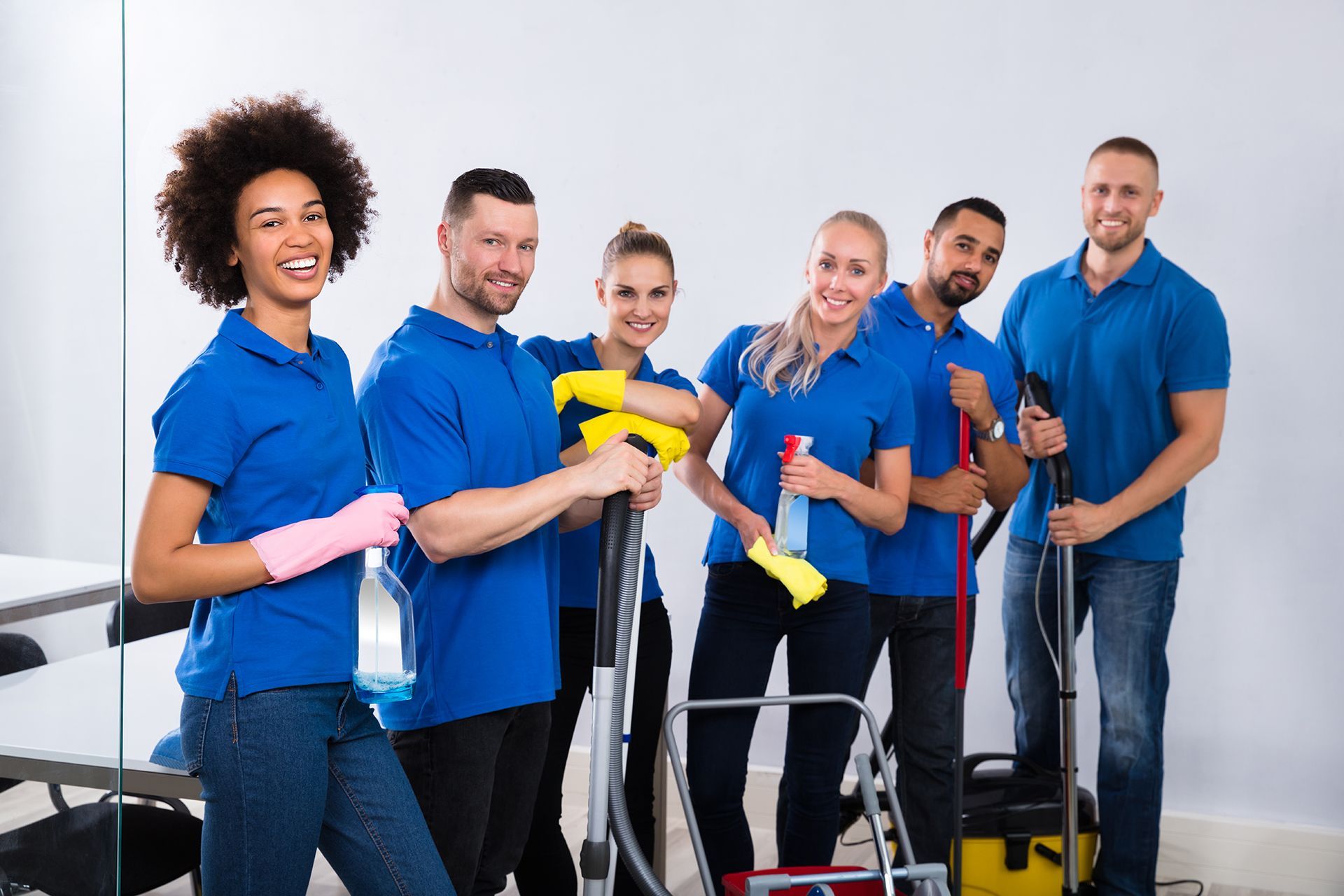 A group of cleaners are posing for a picture while holding cleaning supplies.