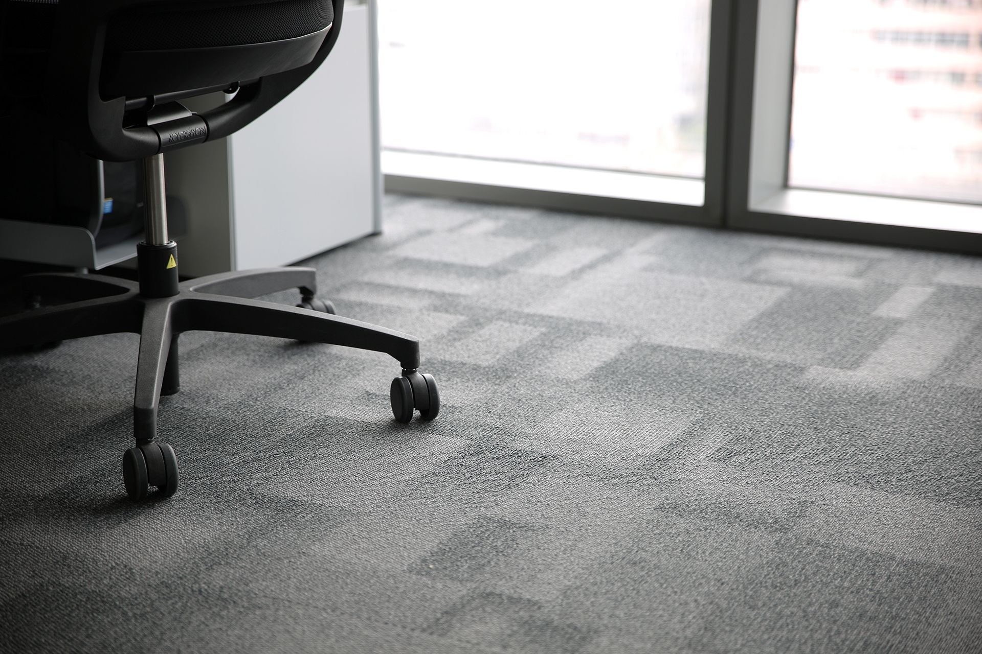 An office chair is sitting on the floor in front of a window.