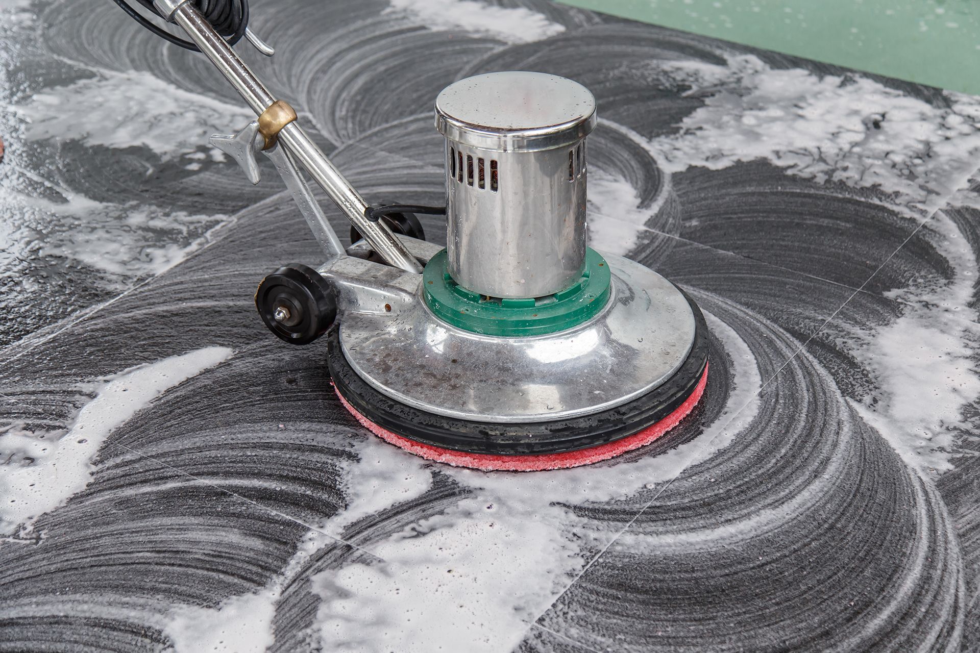 A person is cleaning a tile floor with a machine.