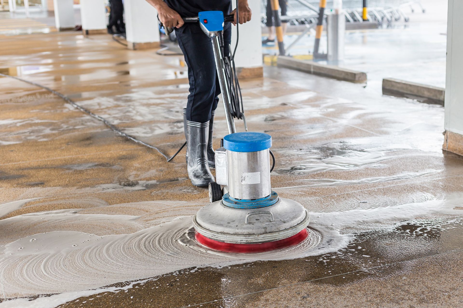 A man is cleaning a concrete floor with a machine.