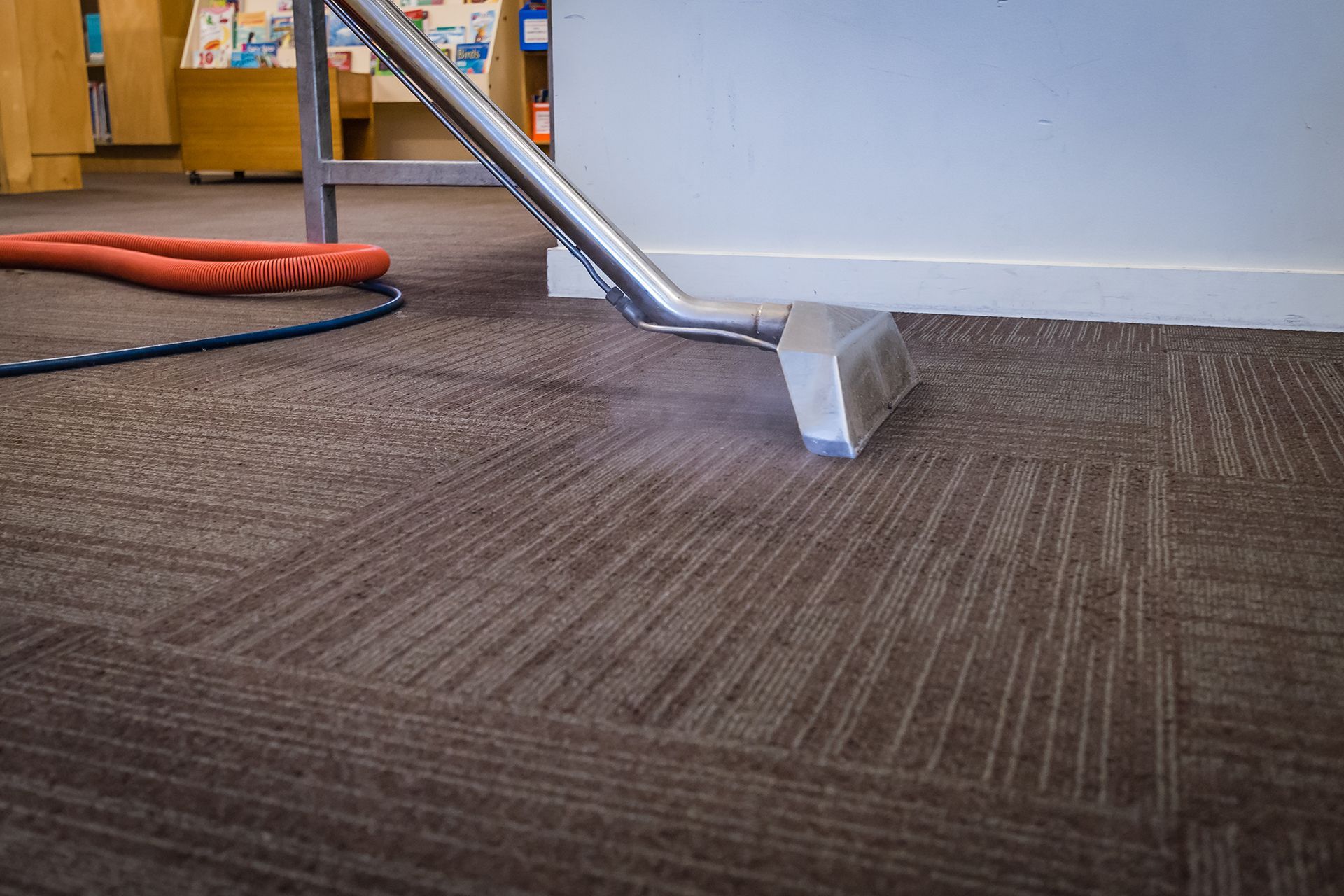 A vacuum cleaner is cleaning a carpet in a room.