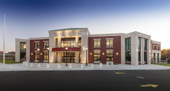 Brick building with light-colored stone accents, glass doors, and windows. Exterior view.