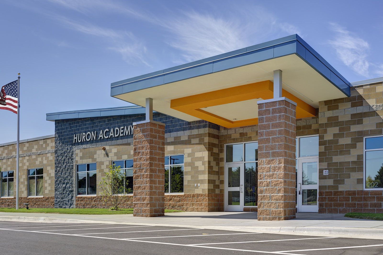 Exterior of Hulon Academy, featuring stone and blue brickwork, columns, and an American flag.