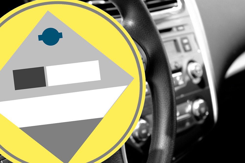 A diamond-shaped warning sign with gray, white, and a blue circle, overlaid on a blurred view of a car interior.