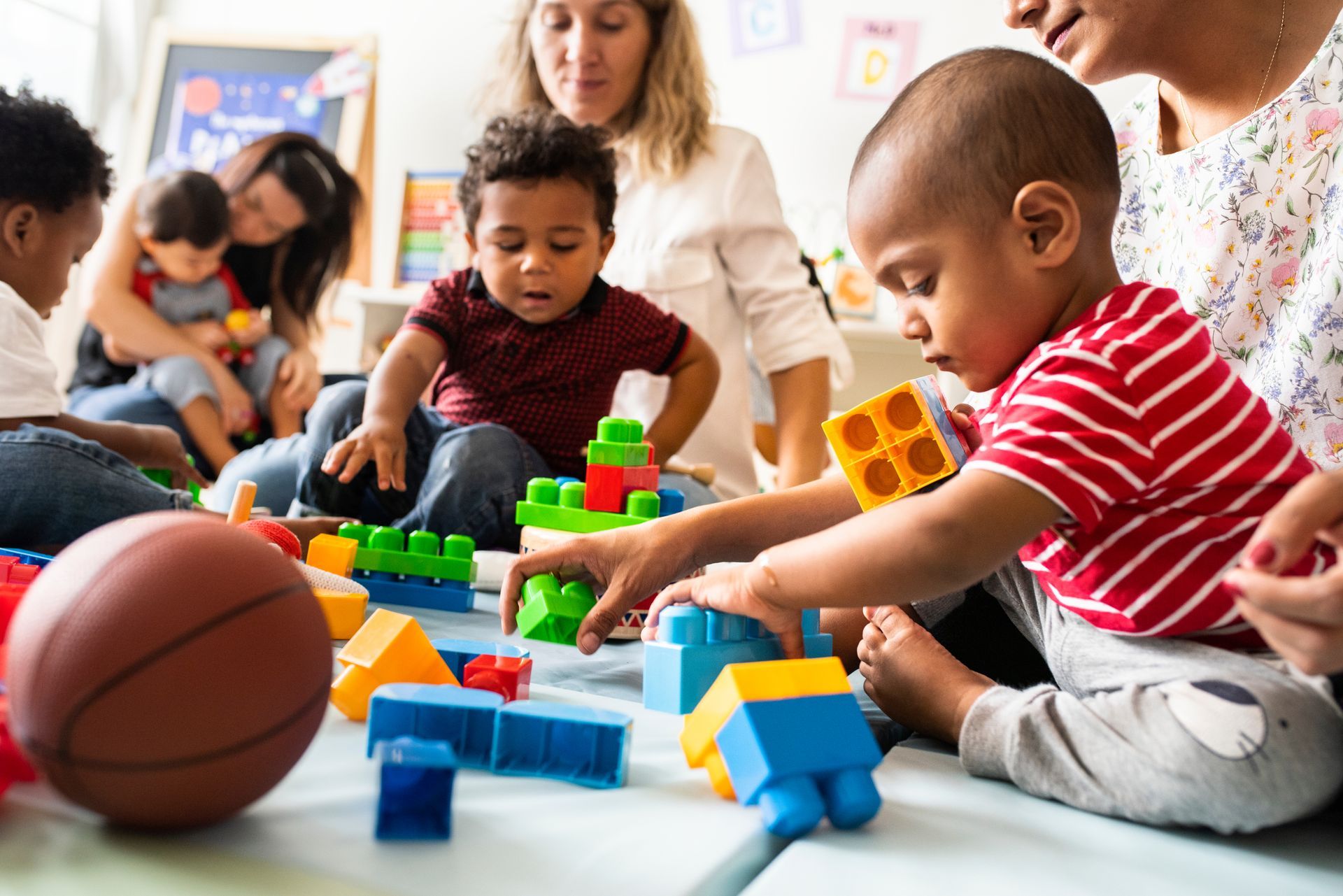 A group of children are playing with blocks on the floor.