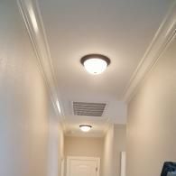 A hallway with two circular ceiling lights and white crown molding against a plain ceiling and light-colored walls.