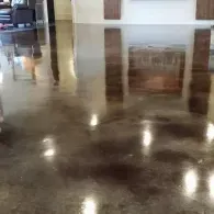 Polished, dark-toned concrete floor reflecting interior architectural elements and soft ambient lighting.