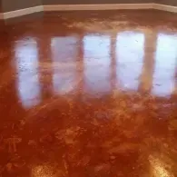 Polished concrete floor with a reddish-brown stain and visible reflections of windows.