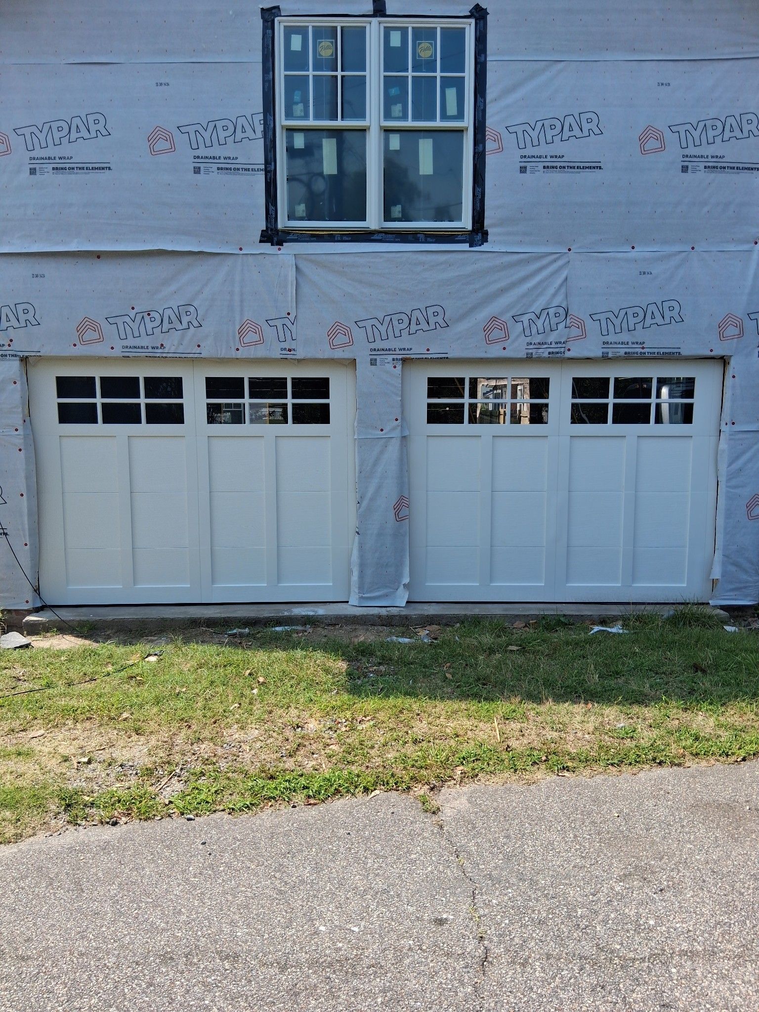 Two white garage doors are sitting next to each other on the side of a house.