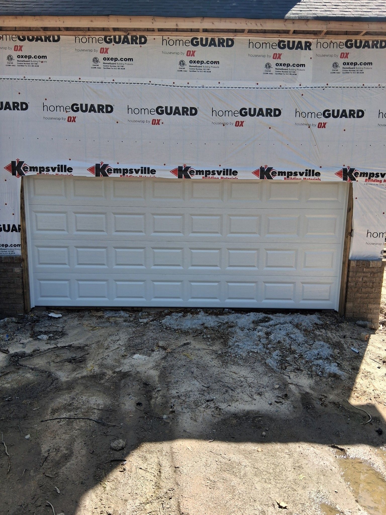 A simple white garage door is sitting in front of a house.