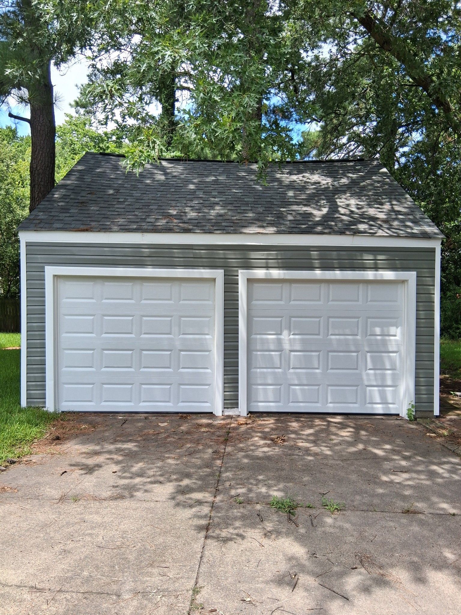 A garage with two white garage doors and a roof.