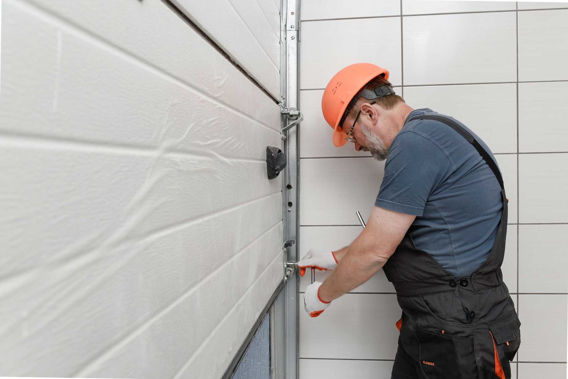 A man is fixing a garage door with a screwdriver.