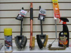 Assorted grill cleaning brushes  neatly arranged on a shelf.