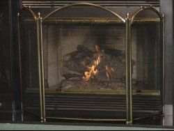 A cozy fireplace with a crackling fire, casting a warm glow in a dark room.