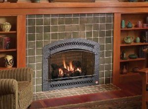 A comfortable chair facing a fireplace surrounded by bookshelves