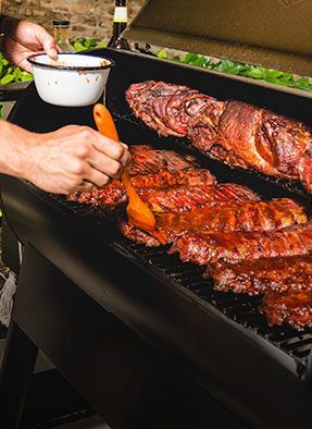 A man grilling ribs on a barbecue outdoors.