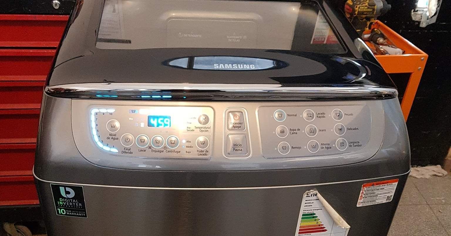 Lavadora de carga superior con panel de control y pantalla digital. Acabado en acero inoxidable y tapa negra.