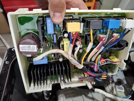 Placa de circuito electrónico con varios componentes, cables y disipador de calor, sostenida por una mano.