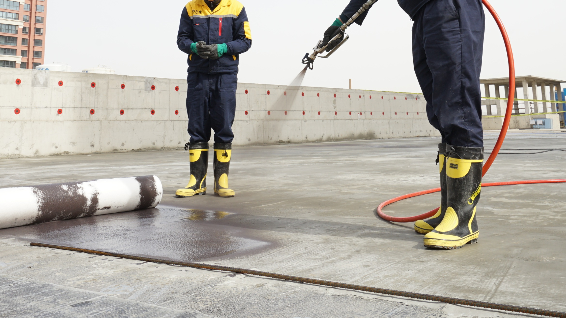 Two men are spraying a concrete surface with a hose.