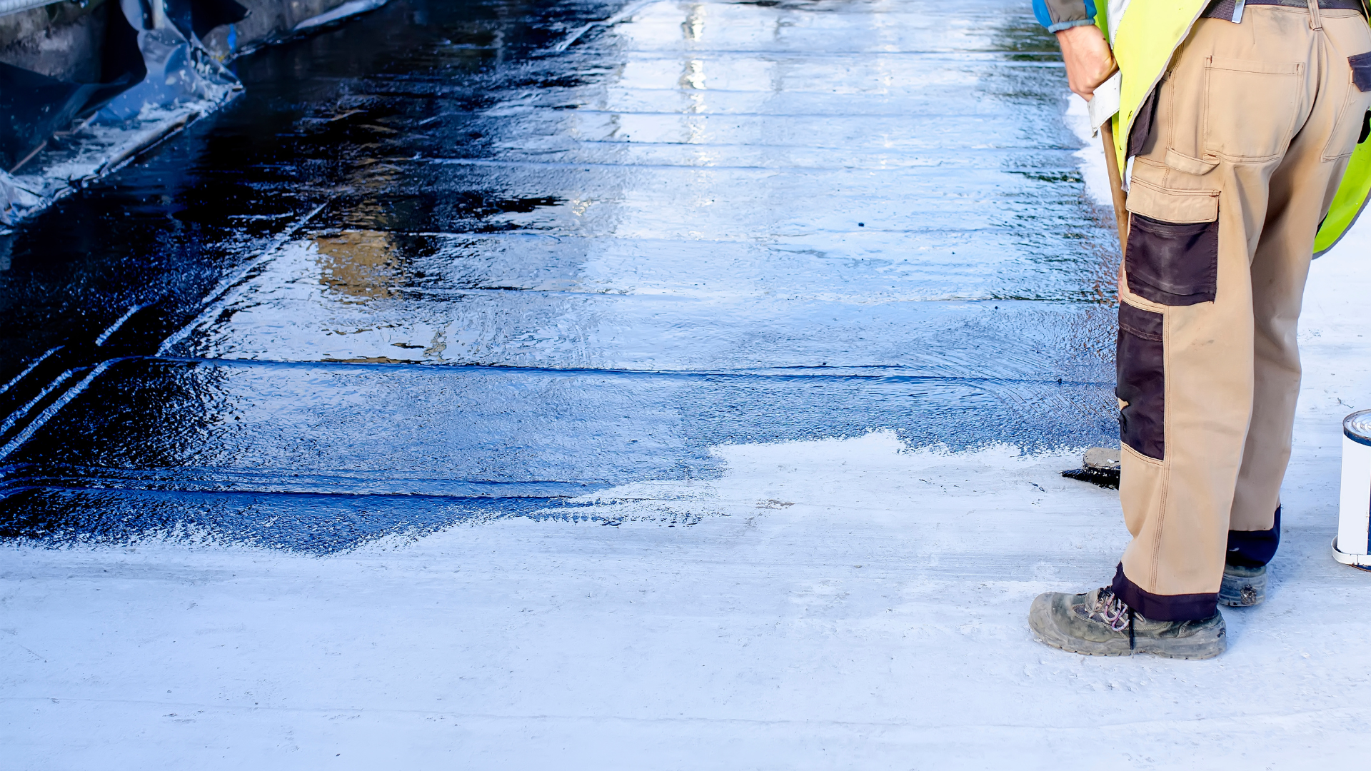 A man is painting a concrete surface with a brush.