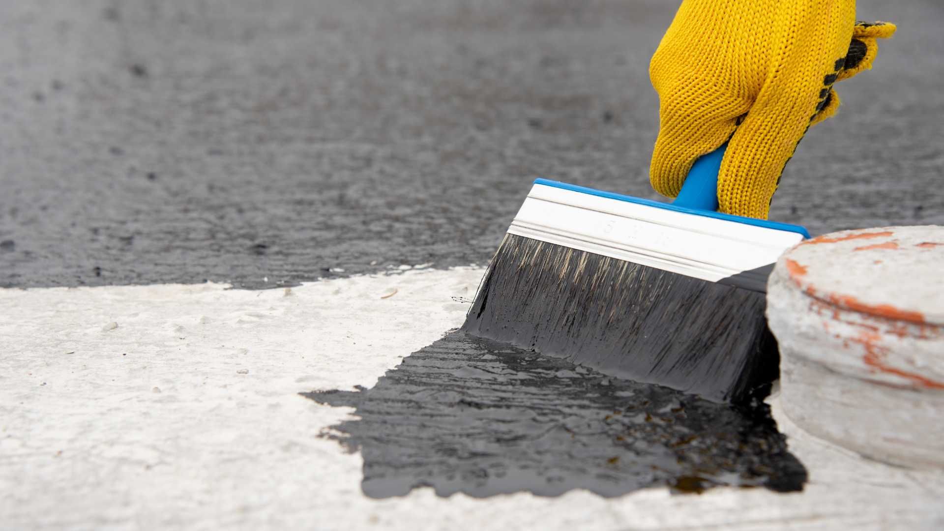 A person is painting a concrete surface with a brush.