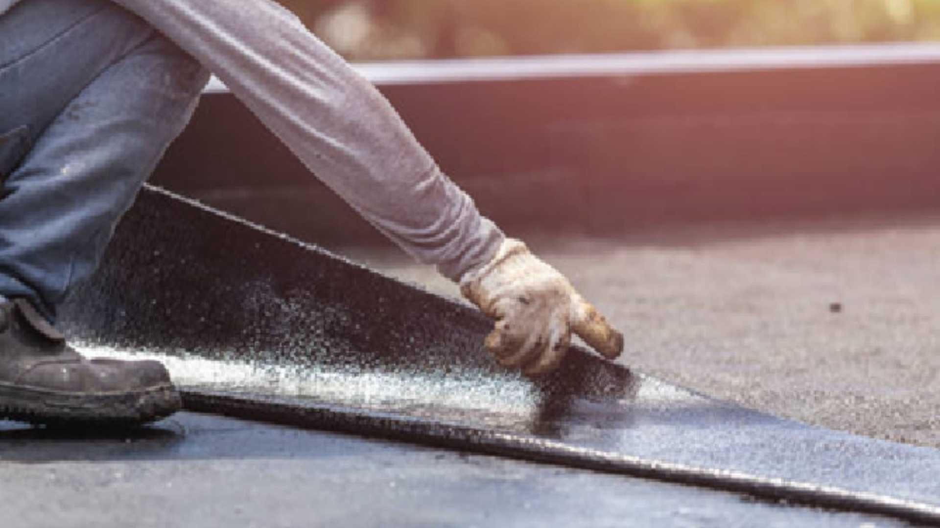 A man is applying a roof coating to a roof.