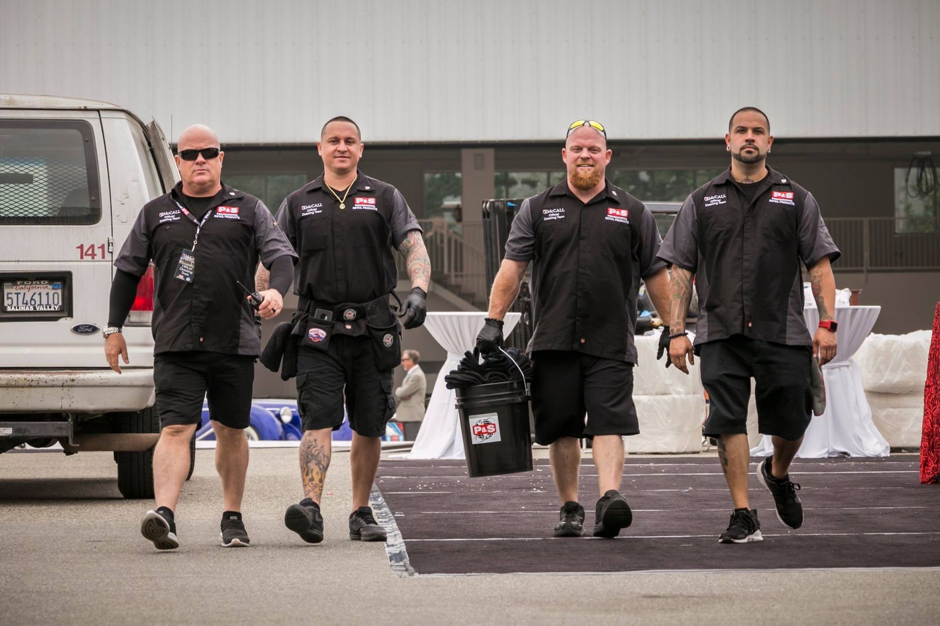 A group of men are walking down a street carrying buckets.