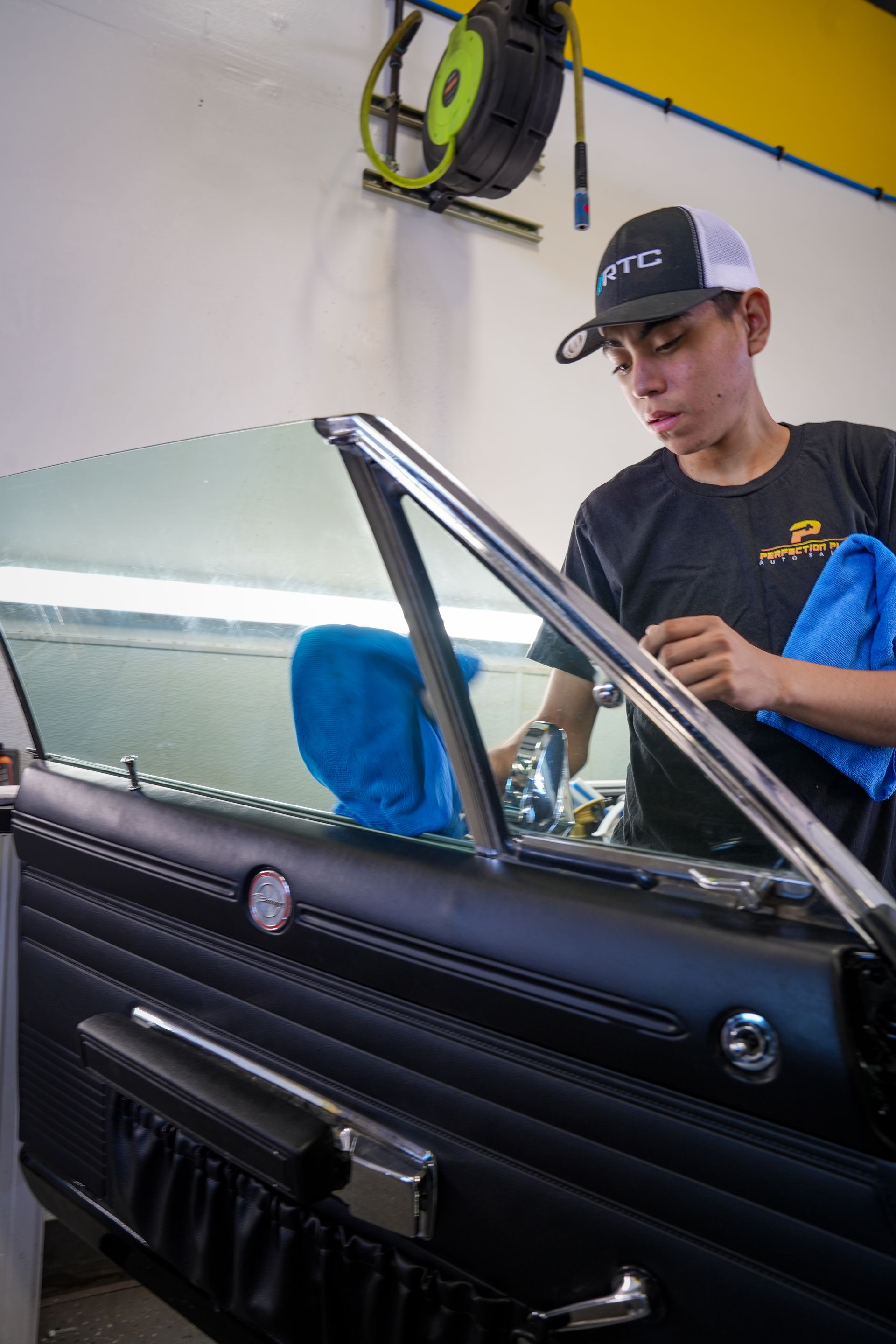 A man is cleaning the window of a car with a towel.