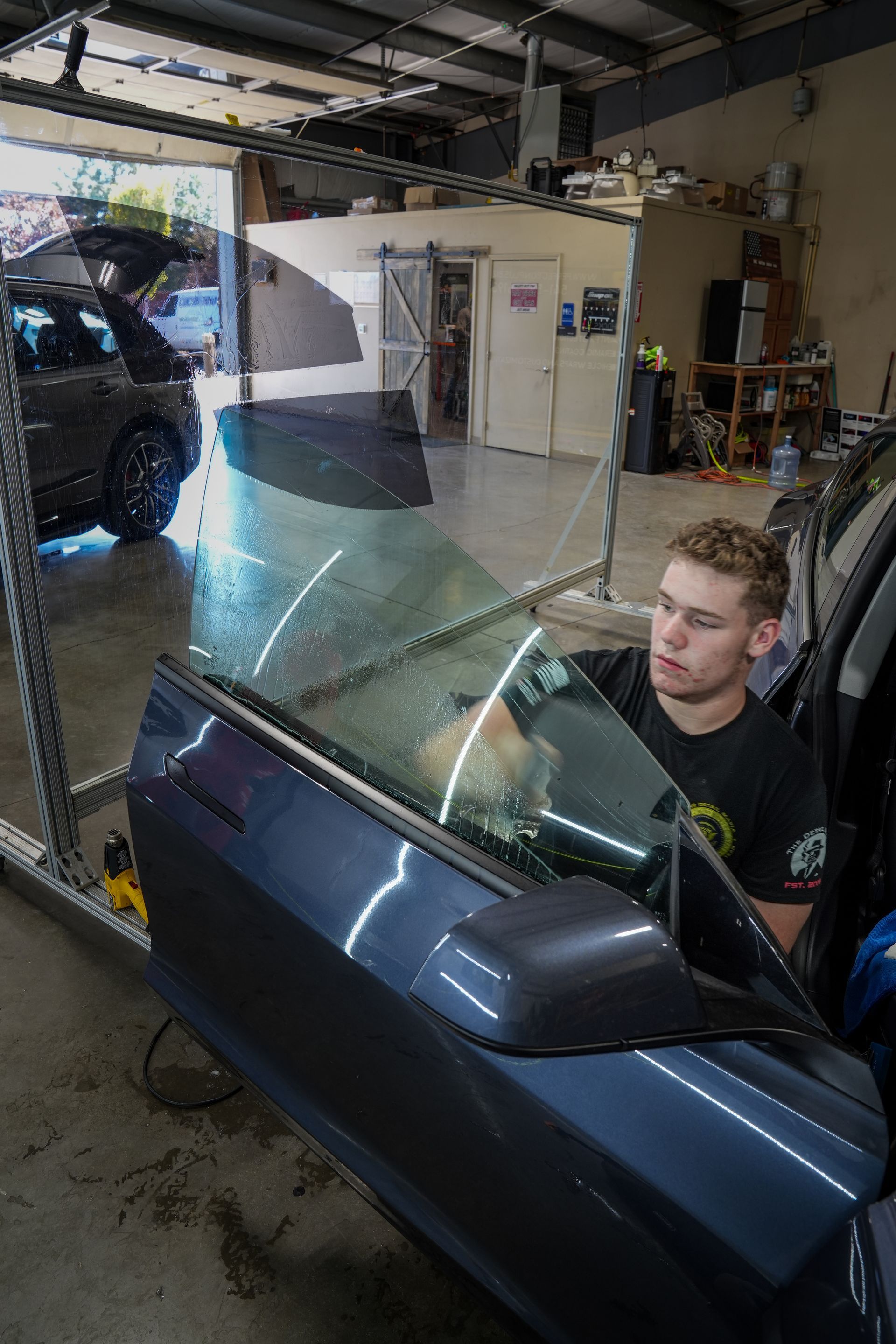 A man is working on a car window in a garage.