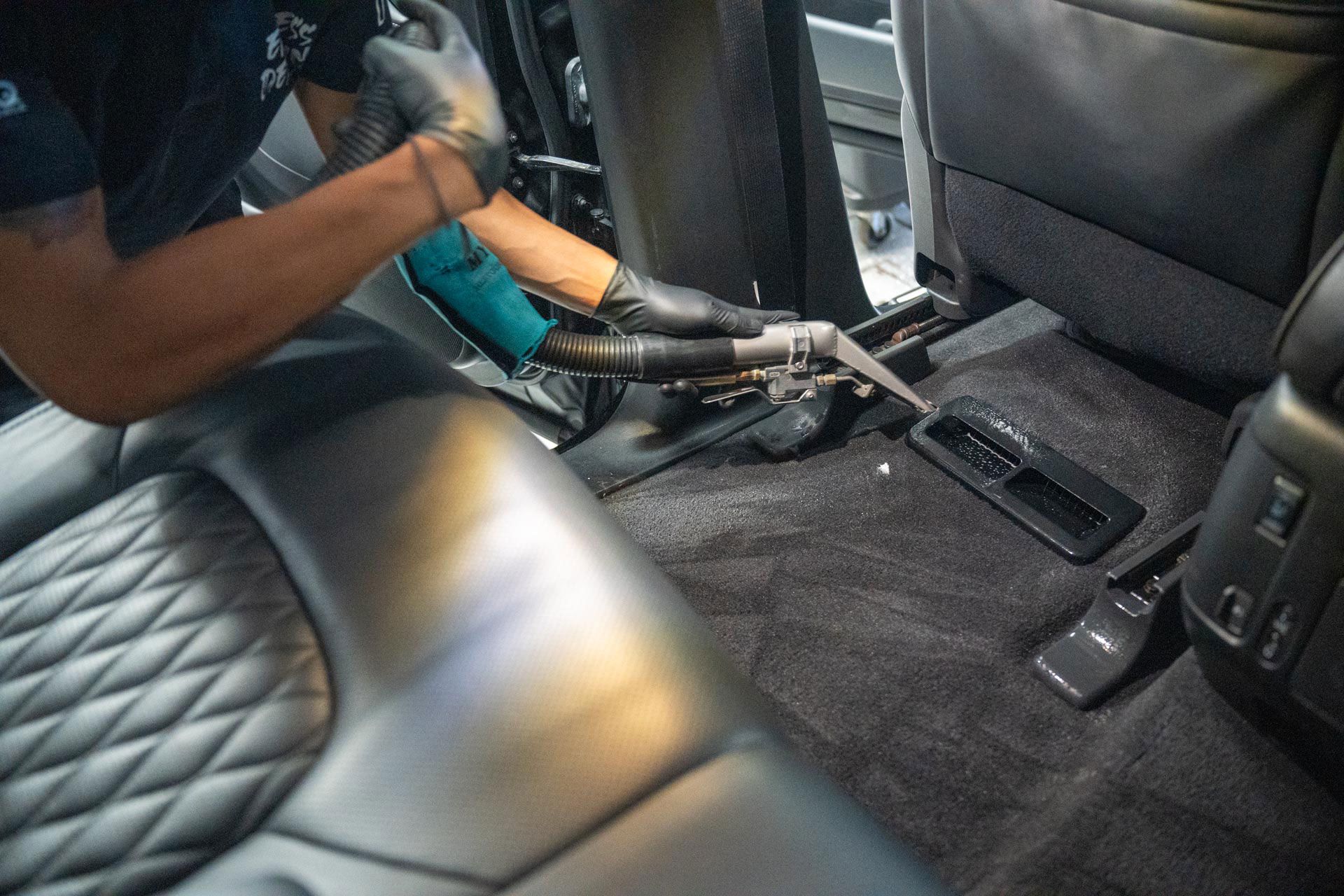 A man is cleaning the interior of a car with a vacuum cleaner.