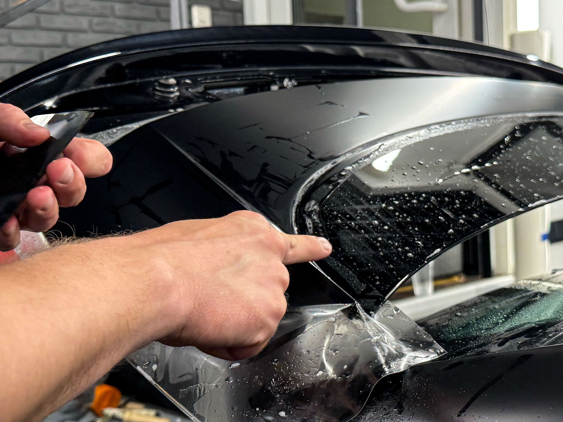 A black suv is parked in a garage with the hood open.