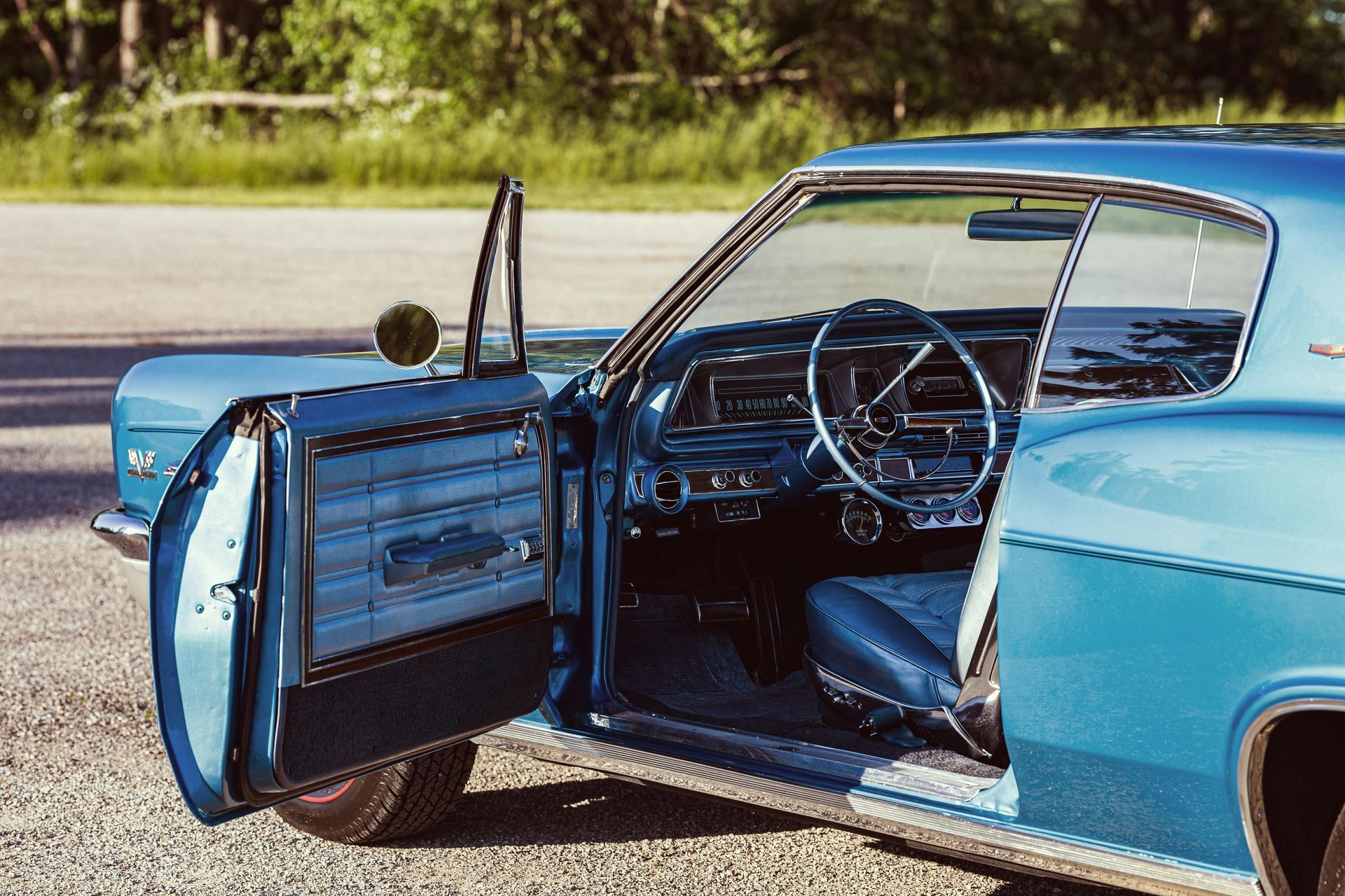 A blue car with its doors open is parked on the side of the road.