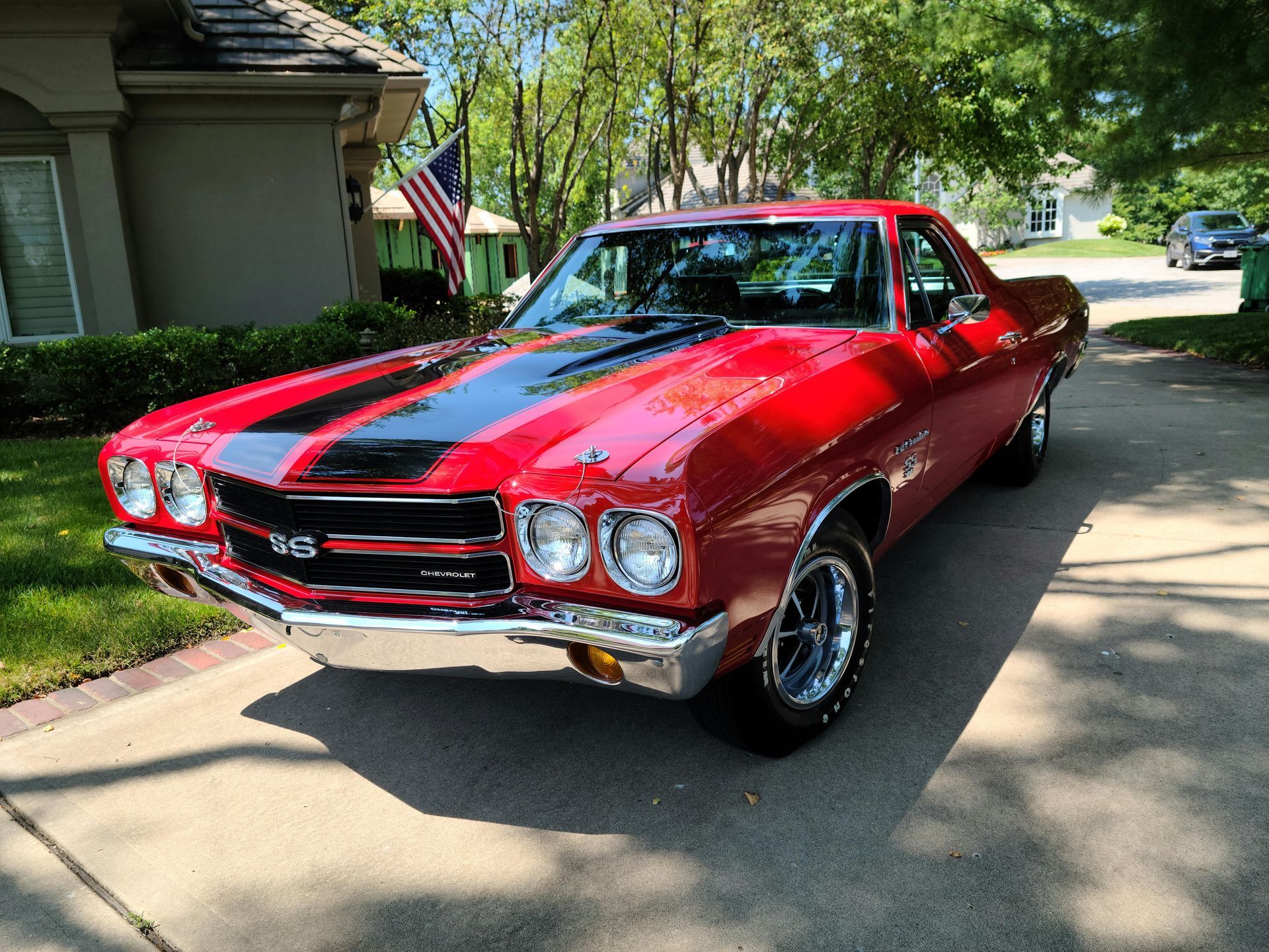 A red chevrolet el camino is parked in front of a house.
