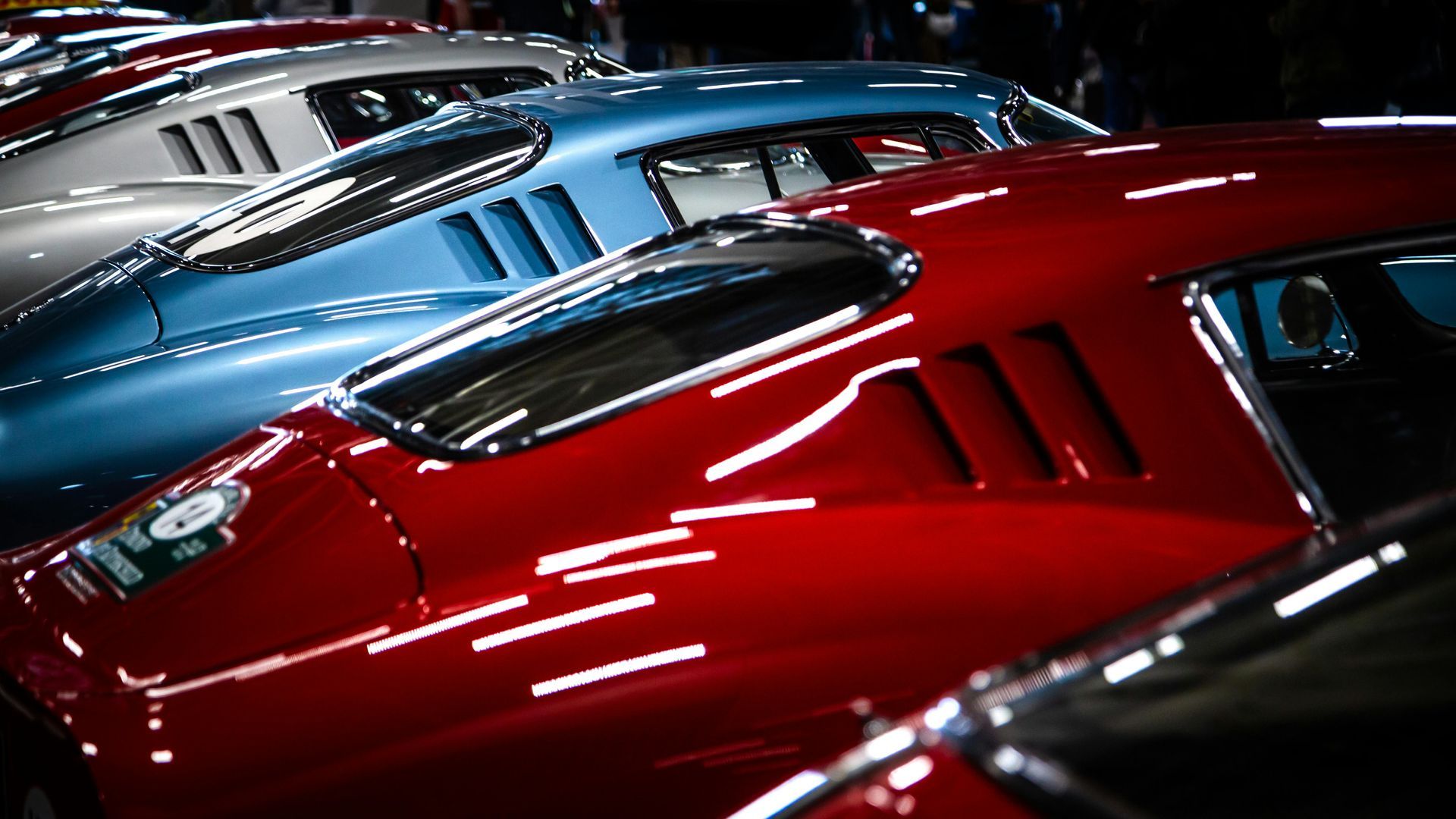A row of red and blue cars are parked next to each other.