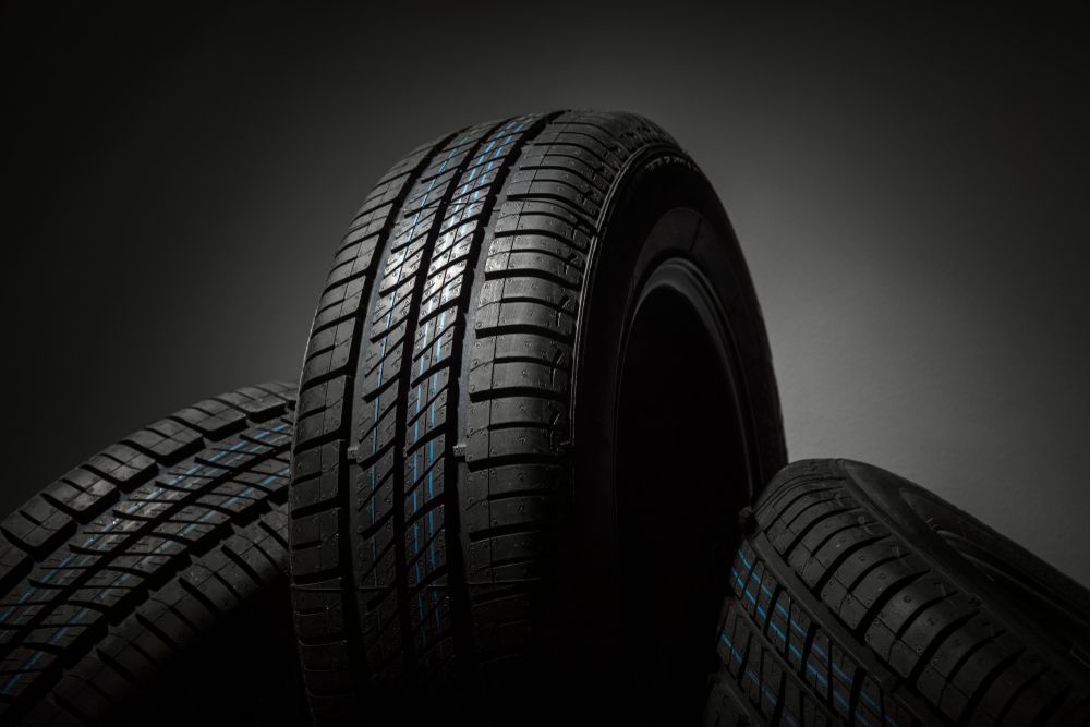 Three New Black Rubber Car Tires Stacked Against A Dark Grey Background — THG Tires in Gladstone Central, QLD