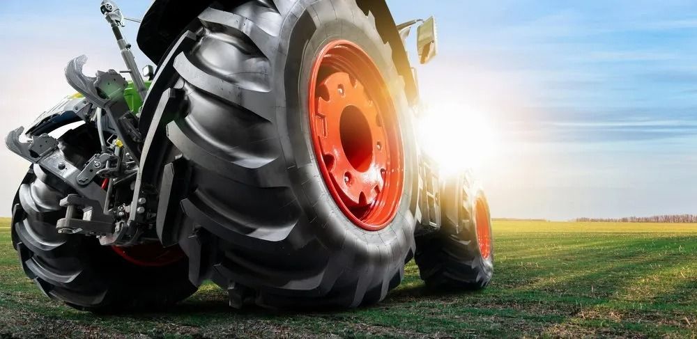 Close-up Of A Large Tractor Tire On A Field With A Bright Sun Flare In The Background — THG Tires in Gladstone Central, QLD