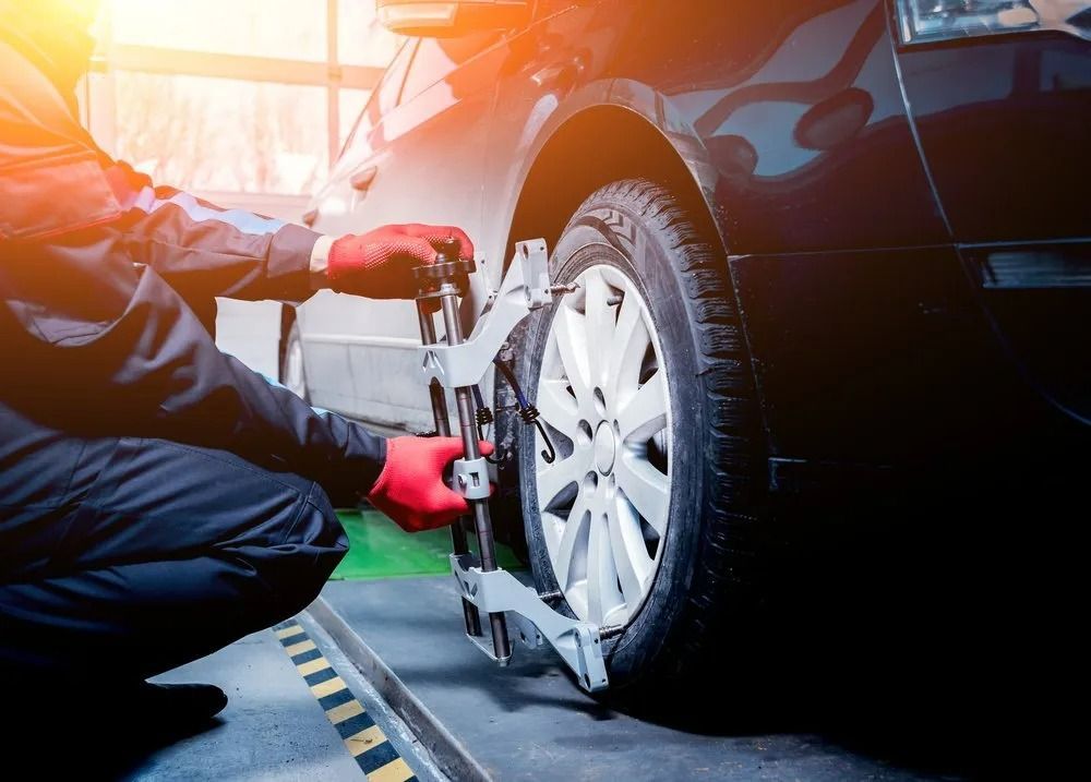 A Technician In Red Gloves Attaches A Wheel Alignment Sensor — THG Tires in Gladstone Central, QLD