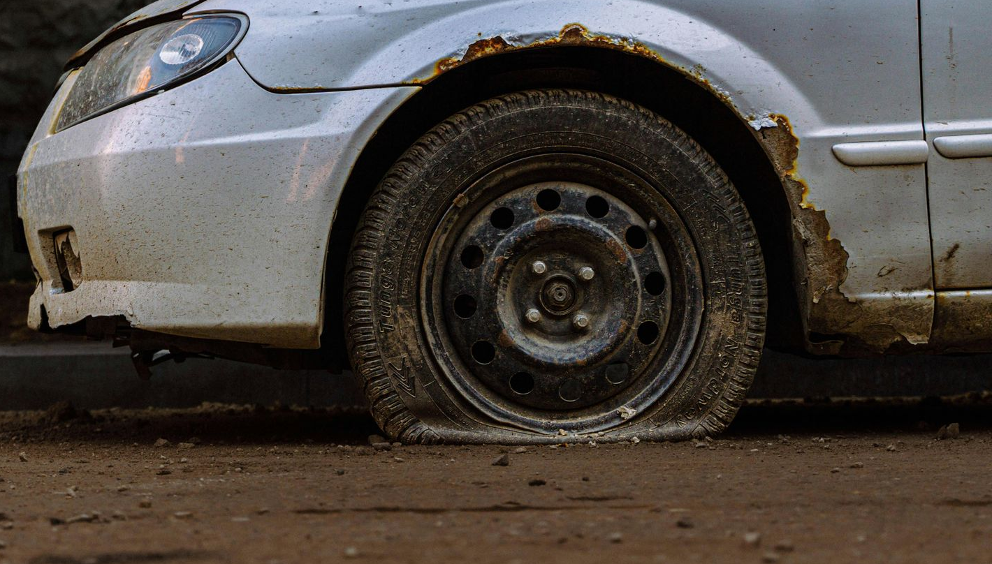 A Mechanic In Blue Overalls Walking In A Garage — THG Tires in Gladstone Central, QLD
