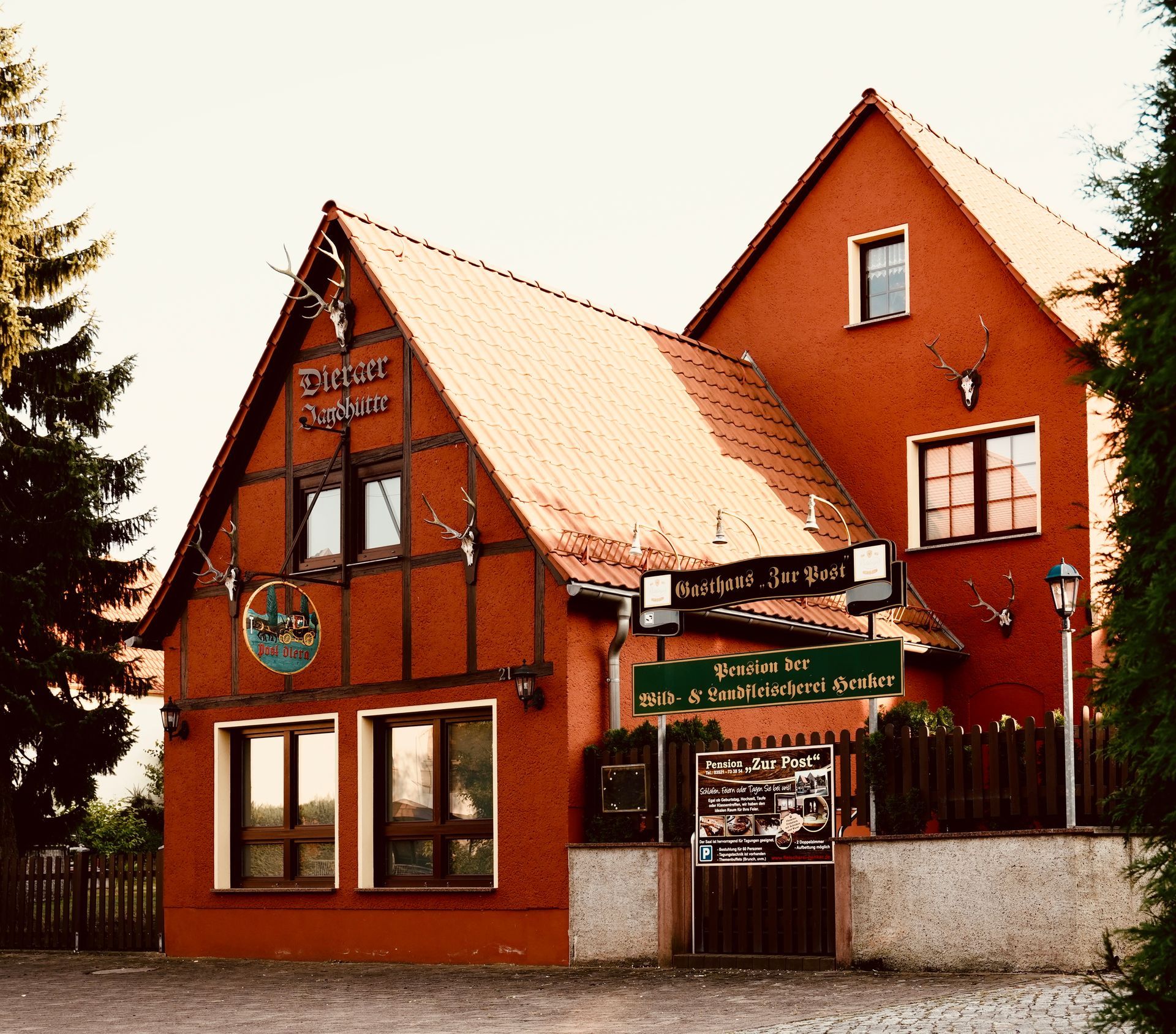 Rot gestrichenes Gebäude mit Satteldach, wahrscheinlich ein Restaurant, mit Schildern, Fenstern und Geweihverzierungen.